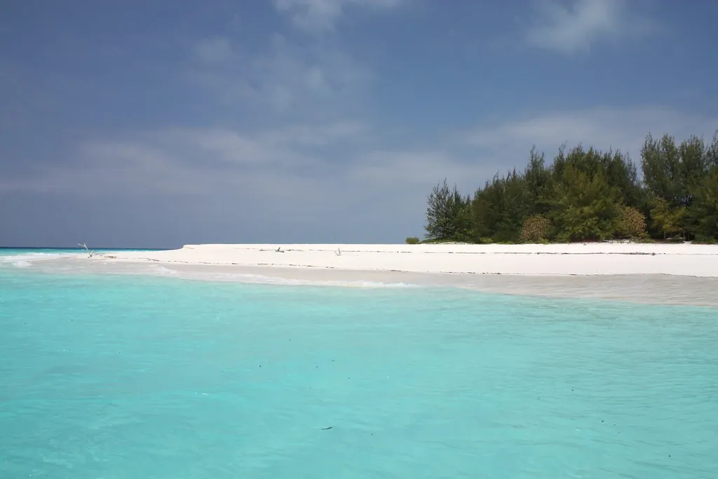 Long white sandbar curving out from a wooded island into turquoise water