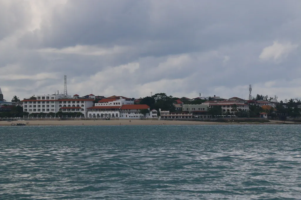 The Stone Town waterfront seen across the sea from a boat, with large white seafront buildings