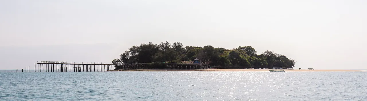 Panorama of low, wooded Changuu island with its long wooden jetty, seen from the sea