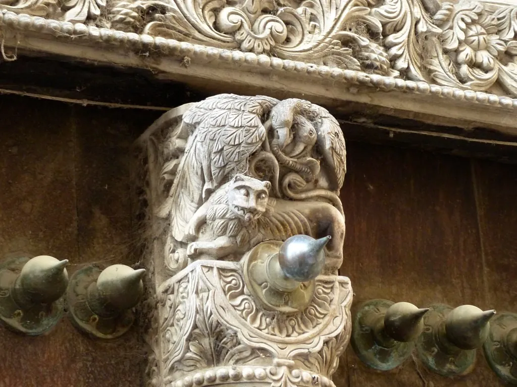 Close-up of a carved door frame with pointed brass studs on the door