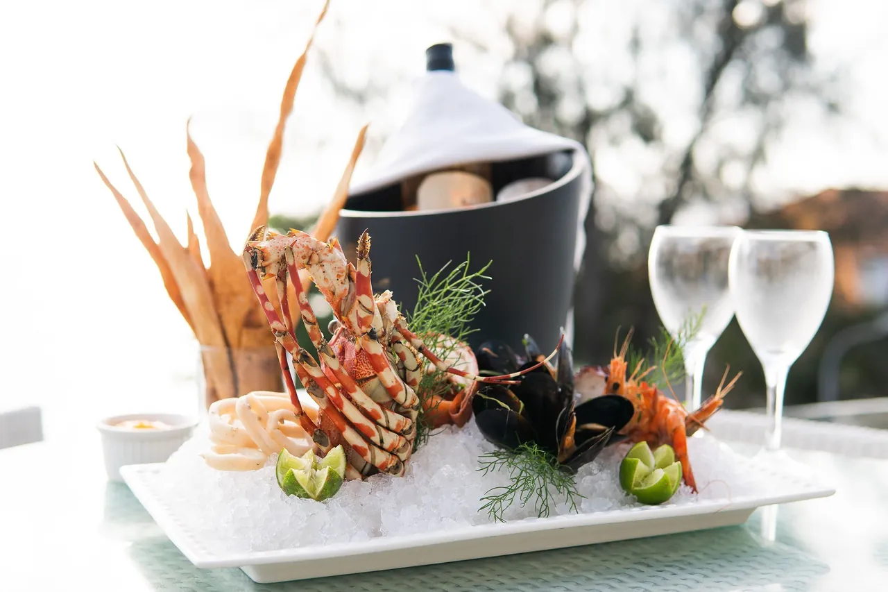A seafood platter with lobster, mussels and calamari on ice beside a wine bucket
