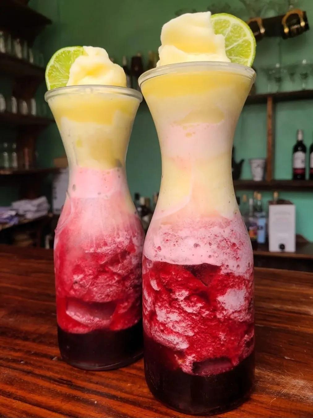 Two tall glasses of layered red hibiscus and lemon juice