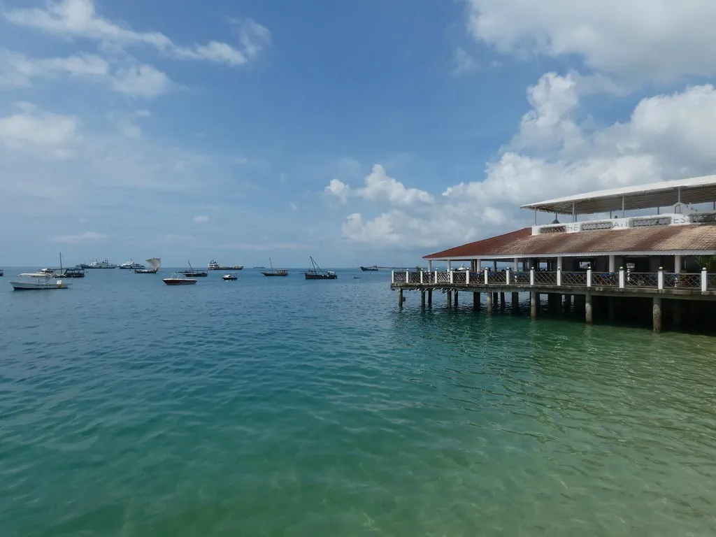 A long pavilion on stilts over turquoise water off the Forodhani seafront, with boats moored offshore