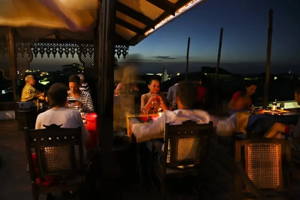 Diners at candlelit tables on the Tea House rooftop after dark
