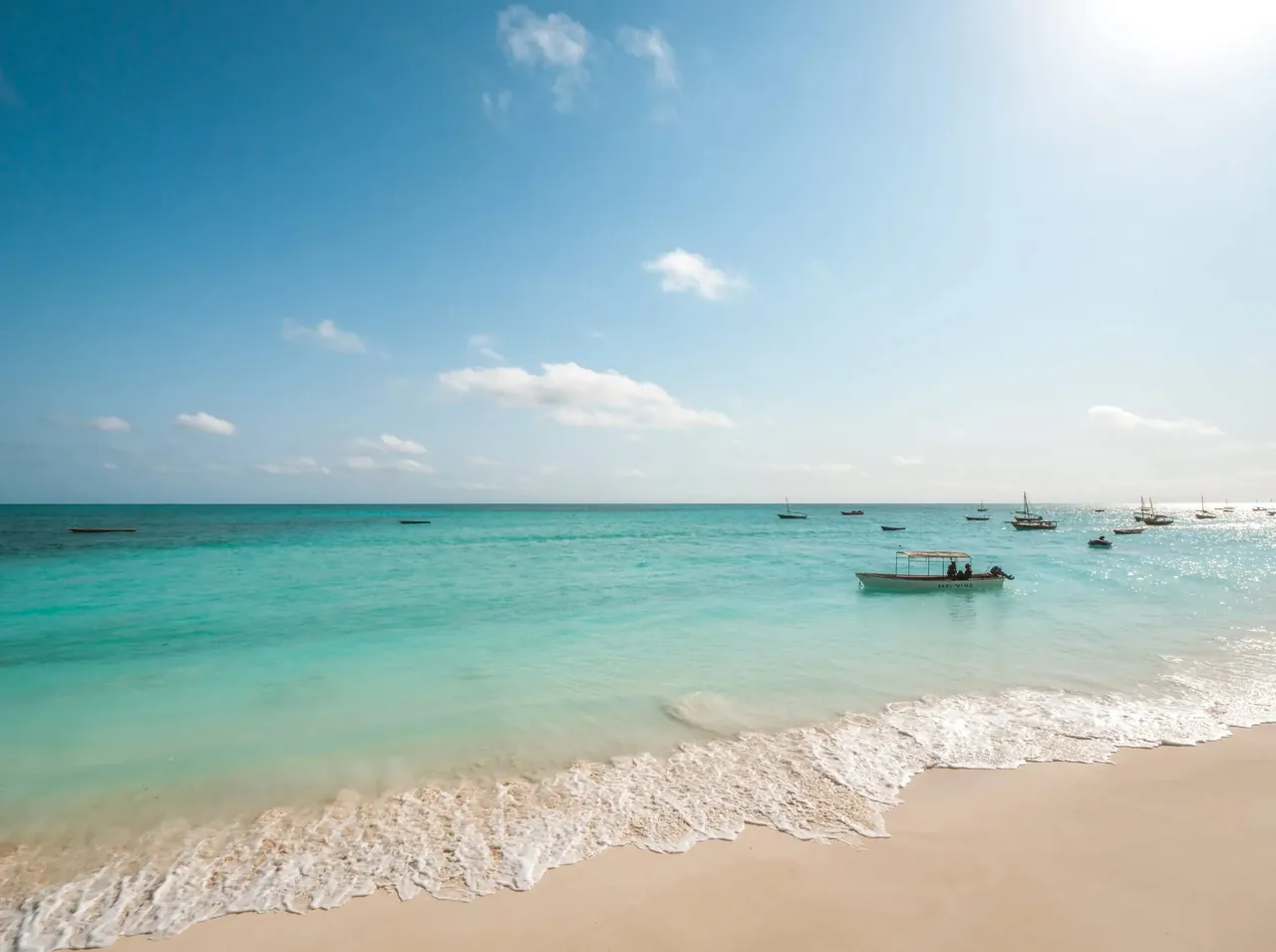 Turquoise water, small boats and white sand on the beach in front of the resort