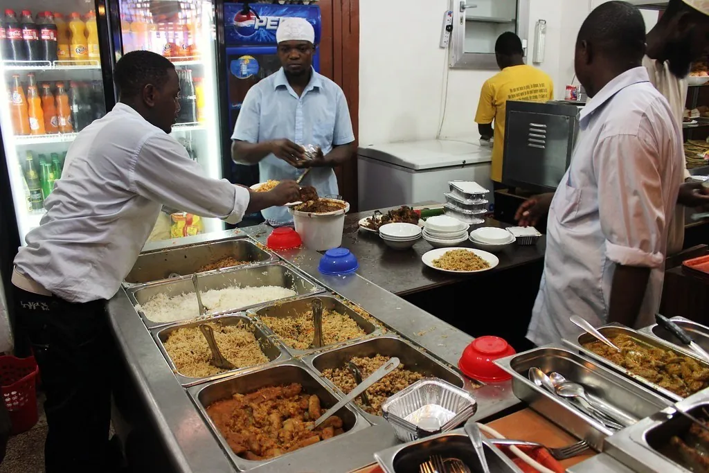 Staff serving from steel trays of curries, rice and stews at the counter